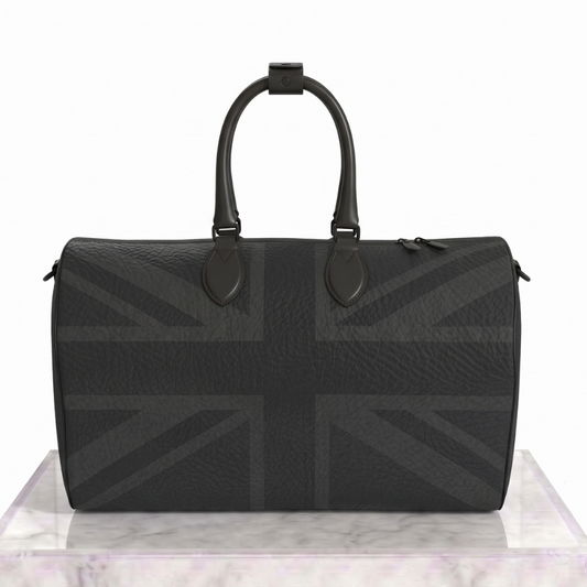 A black pebbled leather duffel bag with a subtle tonal Union Jack pattern, displayed on a white marble pedestal against a white background.